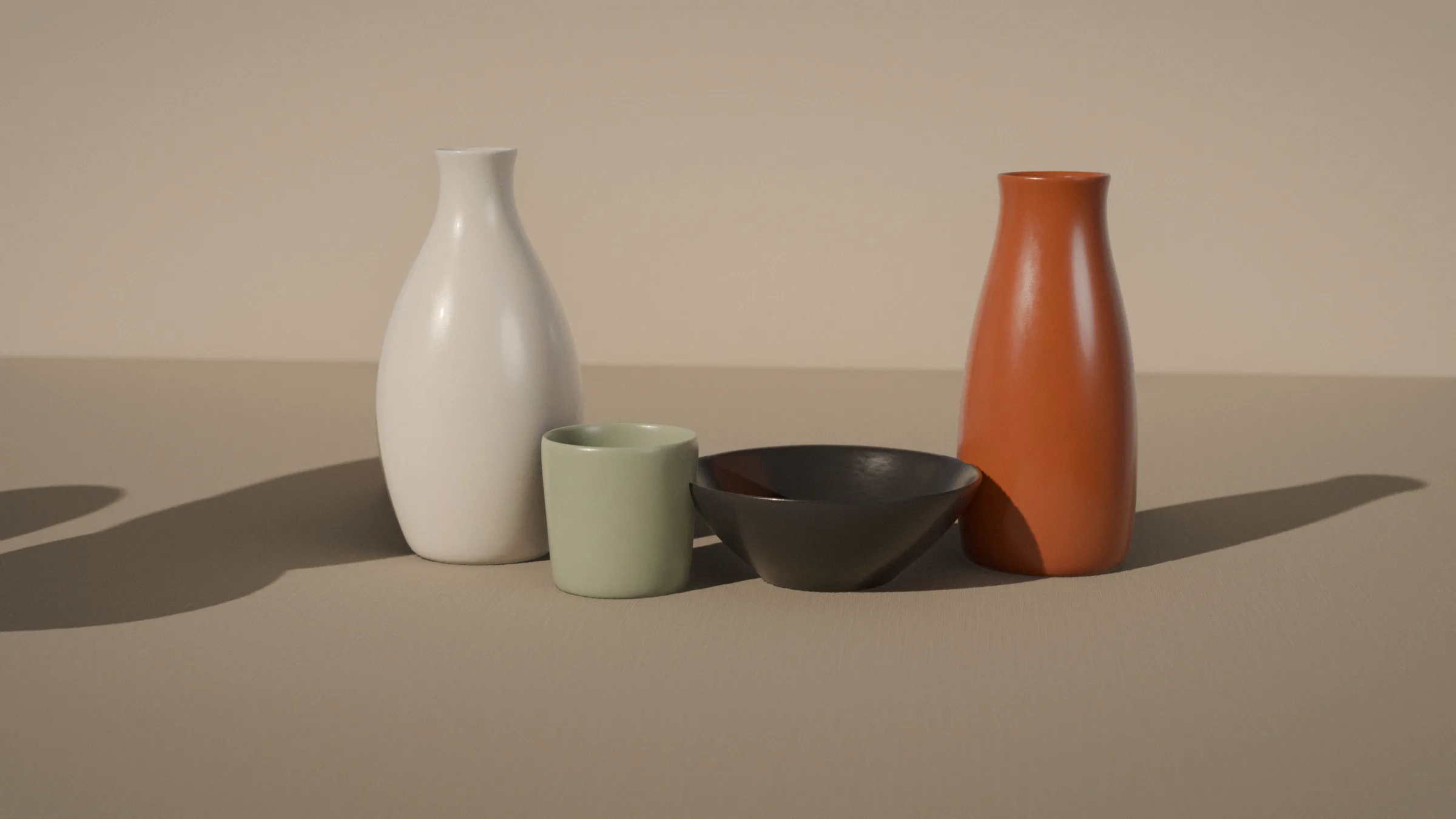 The four hollow pieces on linen in late sun: a chalk vase, a sage tumbler, an ink bowl and a rust carafe
